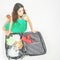 Young woman packs her things, clothes at full luggage
