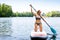 Young woman paddling on sup board on a lake. Active woman on modern trendy stand up paddle board. Summer outdoors