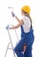 Young woman painter in blue builder uniform standing on ladder w