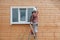 A young woman paints the outside wall of a new wooden house