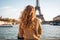 Young woman in Paris looking at the Eiffel Tower, France, Young traveler woman rear view sitting on the quay of Seine River