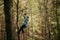 Young woman in park clambering with ropes in forest.