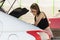 Young woman in the parking lot of a supermarket with a trolley,puts products in the trunk of a car