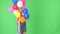 Young woman peeking behind colorful helium balloons