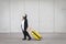 Young woman, with penguin costume and yellow suitcase, has to travel due to global warming