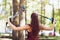 A young woman performs an exercise to work out the muscles of the back on an overhead machine attached to a tree in the park