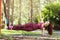 A young woman performs a side plank exercise on a suspended machine attached to a horizontal bar in a park