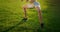 A young woman performs a static exercise on the grass for the leg and hip muscles. To rise on toes while sitting