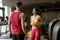 Young woman and personal trainer rest in the gym after workout