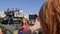 Young woman photographed on mobile phone near large tank and children are sitting on roof of green military vehicle