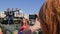 Young woman photographed on mobile phone near large tank and children are sitting on roof of green military vehicle