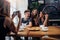 Young woman photographing her positive friends in coffee house using smartphone, background defocused