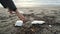 Young woman pick up polystyrene plastic from dirty ocean coast after sea storm