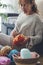 Young woman picking wool from basket while sitting on floor at home. Beautiful woman preparing to knit wool while relaxing at home