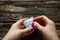 Young woman pierces a condom on wooden background