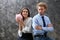 Young woman with piggy bank and her displeased husband on grey background