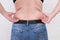 Young woman pinches the fat on the side of her waist to show the flab, overweighted fat body as s result of improper diet