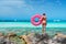 Young woman with pink donut swim ring on the stone in the sea