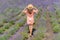 Young woman with pink dress and hat enjoying the beauty and fragrance of a filed of lavender in bloom