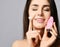 Young woman with pink face exfoliator brush silicone cleansing device for sensitive normal skin and cream and relishes softness