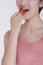 Young woman in pink shirt eating a strawberry, studio shot, half face showing