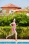 Young woman in pink sportswear runs along poolside