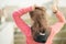 Young woman in a pink suit getting ready for sports training in the early summer morning. collects hair in the tail with