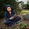 A young woman plants strawberries in a farmer`s garden in the summer. Happy family spending time together. A girl in a blue jacke