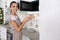 Young woman with plate of croissants near microwave oven