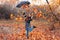 Young woman playing with autumn leaves in park. Autumn rain