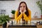 Young woman playing chess on kitchen table. Female plays in logical board game with herself in kitchen.