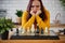 Young woman playing chess on kitchen table. Female plays in logical board game with herself in kitchen.