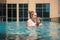 young woman playing with her little daughter in the pool on the roof of a skyscraper in a metropolis