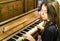 A young woman playing an old vintage piano with closed eyes.