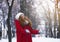 Young woman playing with snowflakes over park background