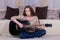 A young woman plays a black acoustic guitar on the carpet in the room