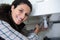 young woman plumber fitting waste on kitchen sink