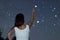 Young woman pointing on defocused Star. Woman under starry night, Woman pointing to Defocused Scorpius Constellation