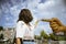 Young woman points the finger the sculpture of a yellow hand, in Museumplein, Museums Square