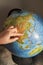 A young woman points her finger at a country on the globe.