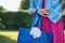Young woman in polka dot dress and denim jacket with bag with peony in the park, image without face, fashion outfit concept