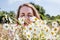 Young woman with pollen sickness sneezing, smelling a daisy bouquet