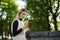 Young woman portrait in summer. Blonde girl is reading message on cell phone outside in city nature. Female with telephone.