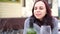 Young woman poses, sitting on street in yard. Female wrapped in grey plaid with alcohol while picnic in winter season.