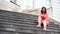 Young woman poses on stairs of manor. Adult female sitting on steps of Palace.