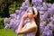 Young woman posing on a park background. Sneezing young girl with nose wiper among blooming trees in park. Pollen