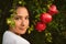 Young woman posing with ripe red pomegranates tree. concept of healthy autumn and winter lifestyle and diet, outdoors with nature