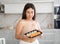 Young woman posing with set of rolls in kitchen