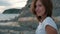 Young woman posing sitting on beach in summer evening outdoors.