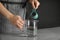 Young woman pouring chia seeds into measuring glass with water at table